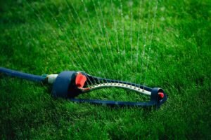 Lawn sprinkler spaying water over green grass.
